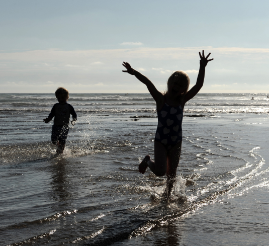 Kids playing on the shore at sunset